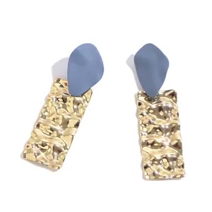 Close up view of geometric matte blue and textured gold drop earrings showing exquisite craftsmanship.