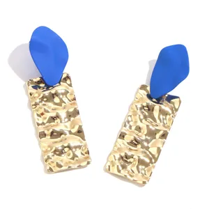 Detailed closeup of handmade blue matte and gold hammered rectangular dangle earrings.