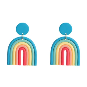 Detailed close-up view of colorful polymer clay rainbow arch earrings with bright blue studs.