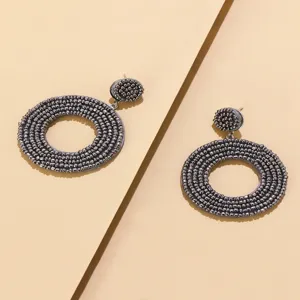 Gedetailleerde close-up van donkergrijze kraal oorbellen met bohemian stijl textuur.