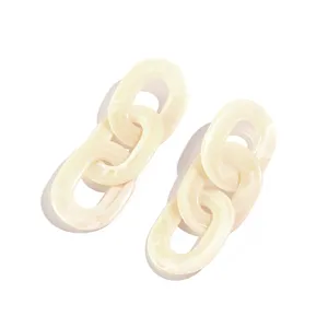 Gedetailleerd overzicht van beige acryl schakeloorhangers, chique retro geometrisch ontwerp.