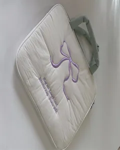 Detailansicht der gesteppten Laptoptasche mit gestickter Schleife und bequemem Tragegriff.