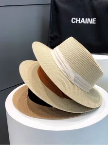 Close-up detail of layered straw sun hats with ribbons on display stand for summer resort.