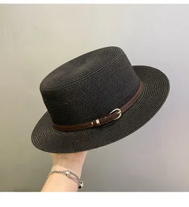 Detail view of a black straw boater hat featuring a stylish brown belt buckle and narrow brim.