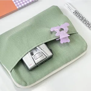 Detailed view of green corduroy laptop sleeve pouch, soft texture with front pocket and zipper.