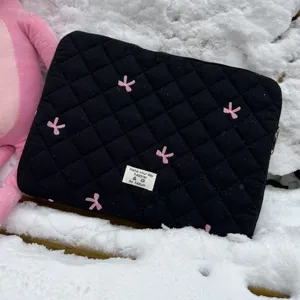 Black quilted laptop sleeve with pink embroidered bows for tablet storage daily use detail view.