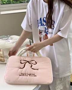 Detailaufnahme einer rosa gesteppten Laptoptasche mit brauner Schleife, weiches stilvolles Design.