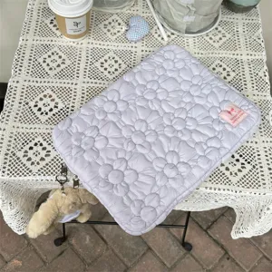 Detail shot of the quilted floral laptop sleeve with cute plush charm and elegant texture.