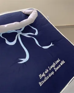 Detailansicht der dunkelblauen Plüsch-Tablettasche mit hellblau bestickter Schleife.