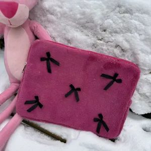 Detailed view of fluffy pink laptop sleeve with sweet black bow decorations and plush fabric.