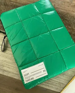 Dettaglio custodia per laptop trapuntata verde, copertina protettiva spessa con etichetta.