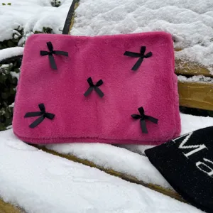 Pink plush laptop sleeve detail featuring soft fuzzy fabric and black bow decorations.
