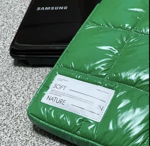 Primo piano dettagliato della custodia per laptop trapuntata verde lucida con etichetta.