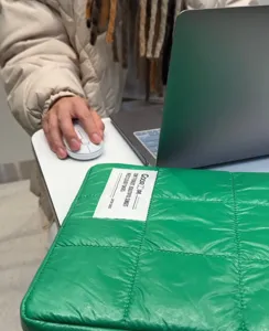 Primo piano dettagliato della texture della custodia trapuntata verde per laptop con etichetta.
