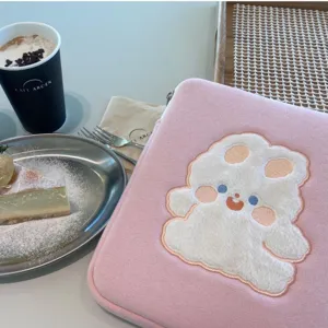 Cute fluffy bear embroidery detail on pink aesthetic tablet sleeve for daily use scene.