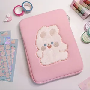 Close-up detail of cute pink tablet sleeve featuring soft plush rabbit design on cozy desk setup.