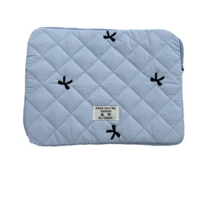 Light blue quilted laptop sleeve with cute bow embroidery for tablet and notebook storage.