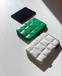 Dettaglio della custodia per laptop imbottita in verde e bianco, design a griglia trapuntata.