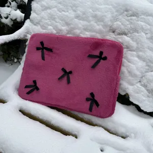 Cute pink plush laptop sleeve with black bow accents, soft fur tablet storage bag for women.