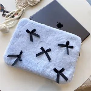 Close-up detail of fluffy light blue laptop sleeve featuring cute black bows, soft texture.