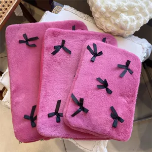 Plush laptop sleeve detail featuring soft pink fabric and cute black bows in various sizes.