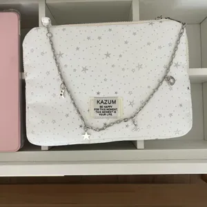 White star pattern laptop sleeve detail, silver chain strap with charms, chic design.