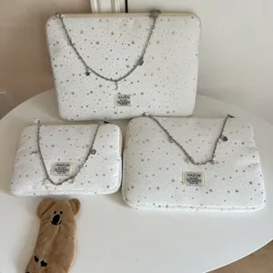 Detailed shot of white laptop sleeves featuring silver star patterns and chain straps, neatly arranged.