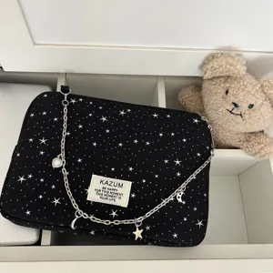 Black star pattern laptop bag with silver chain strap and cute bear prop background.