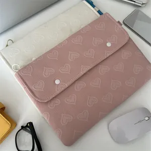 Detailansicht von weissen und rosa Tabletttaschen mit Steppherzmustern auf dem Schreibtisch.