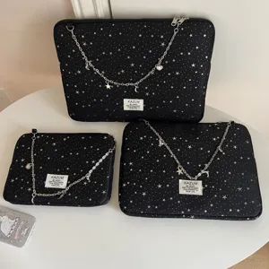 Close-up detail of black star pattern laptop sleeve with silver chain and cute moon star charms.