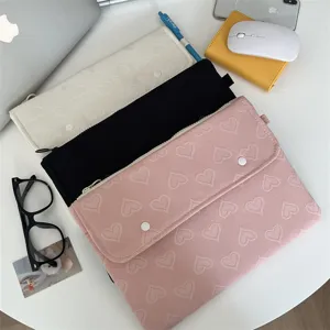 Detailansicht der süßen Herzmuster Tablet-Hülle auf weißem Tisch, weiche Laptoptasche.