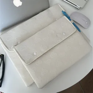 Detailansicht der weißen gesteppten Herz-Laptoptasche auf dem Schreibtisch mit Maus.