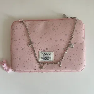 Pink star pattern laptop sleeve detail view with metal chain decoration and woven label.