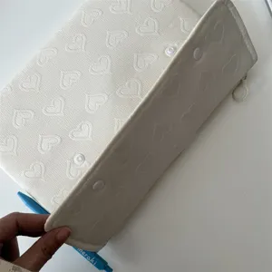 Detailansicht der weichen, gesteppten Tablettasche mit Herzmuster und praktischen Druckknöpfen.
