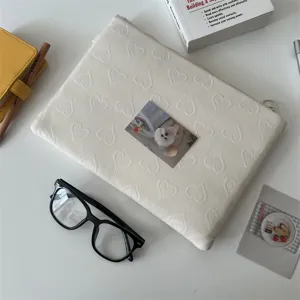 Nahaufnahme der cremefarbenen gesteppten Herz-Tabletttasche mit minimalistischen Deko-Requisiten.