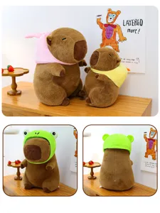 Close-up detail of cute capybara plush toy wearing funny frog hat sitting on wooden desk.