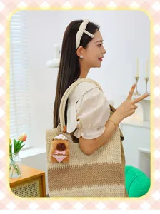 Detail view of straw tote bag with cute knitted capybara bikini keychain pendant in room.