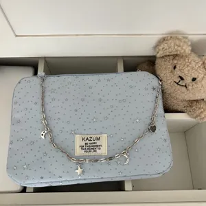 Light blue star print laptop bag with silver chain and cute star moon charms for tablet storage.