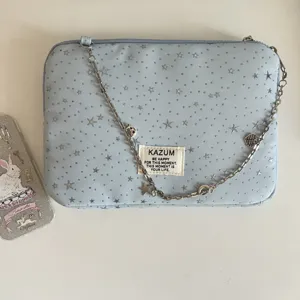 Detail view of the light blue star print laptop sleeve with metal chain and brand label.