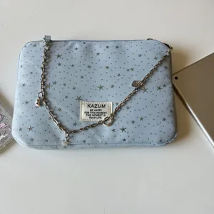Detail view of the light blue star patterned tablet sleeve featuring a delicate metallic chain.