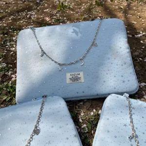 Close-up detail of light blue laptop sleeve featuring star pattern and metal chain.