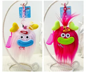 Detail view of funny plush monster keychains with long hair, googly eyes, and cute mini accessories.