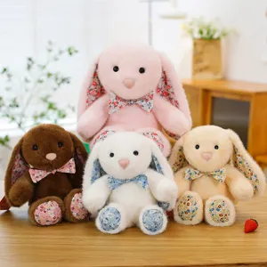 Cute floral plush rabbit toys set, sitting together on wooden table, soft stuffed bunny dolls.