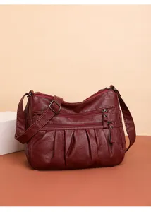 Close-up view of wine red soft leather women crossbody bag with multi zipper compartments.