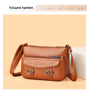 Retro soft leather crossbody bag detail featuring unique heart-shaped metal buckles and zipper.