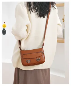 Detail shot of women brown leather crossbody bag worn by model, showing style and retro design.