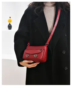 Detail view of red soft leather crossbody phone bag with heart metal decor for women.