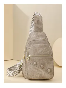 Close-up detail of stylish women crossbody chest bag with wide patterned strap and zipper.