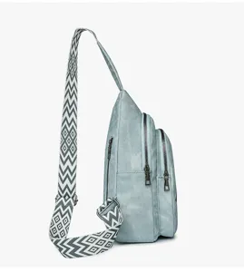 Detailed view of a stylish blue sling bag with geometric pattern strap and double zippers.