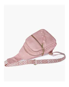 Close-up of pink crossbody chest bag showing gold double zippers, buttons, and patterned strap.